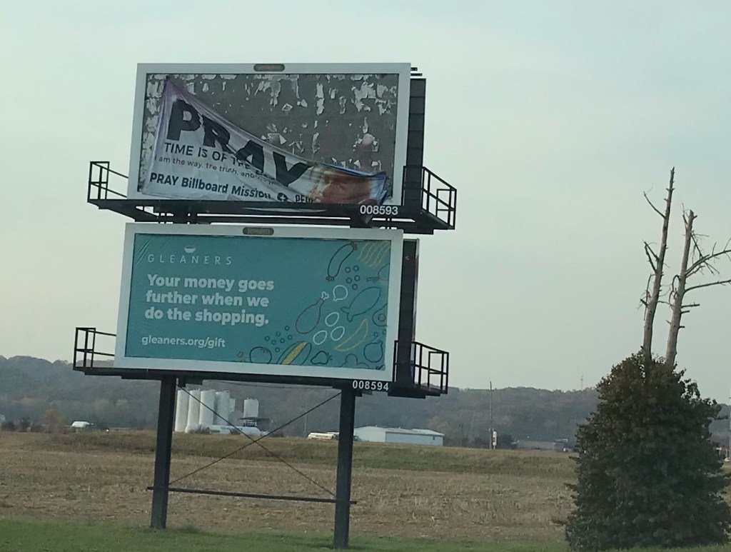 Roadside billboard showing the message "PRAY: Time is of the essence" falling off the advertising platform.